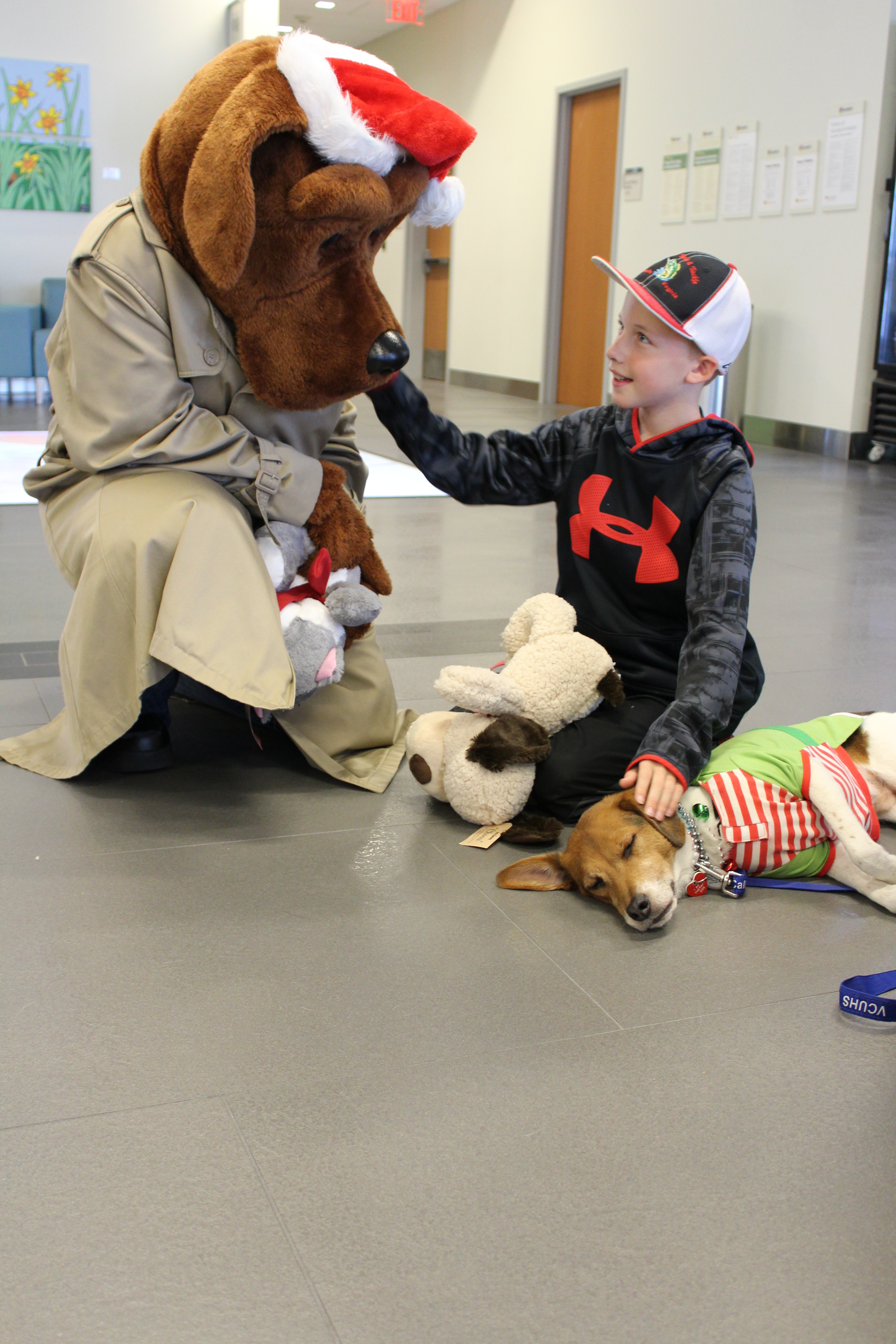  McGruff, the V C U Police mascot and therapy dog Blake, a beagle mix, each receive pets from a generous friend sitting in between them.