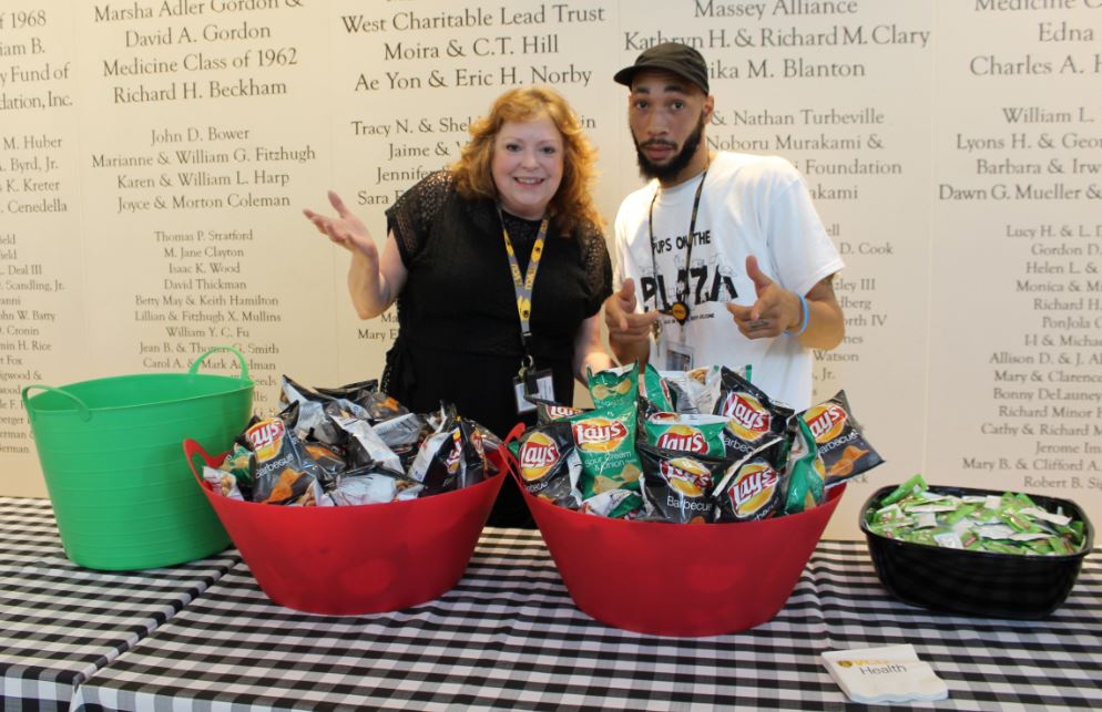 The V C U Health catering team poses in front of bags of chips and condiments at the Pups on the Plaza event