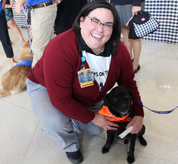 Dogs On Call therapy dog Otis, a black lab and pug mix, is hugged by a V C U Health team member. 