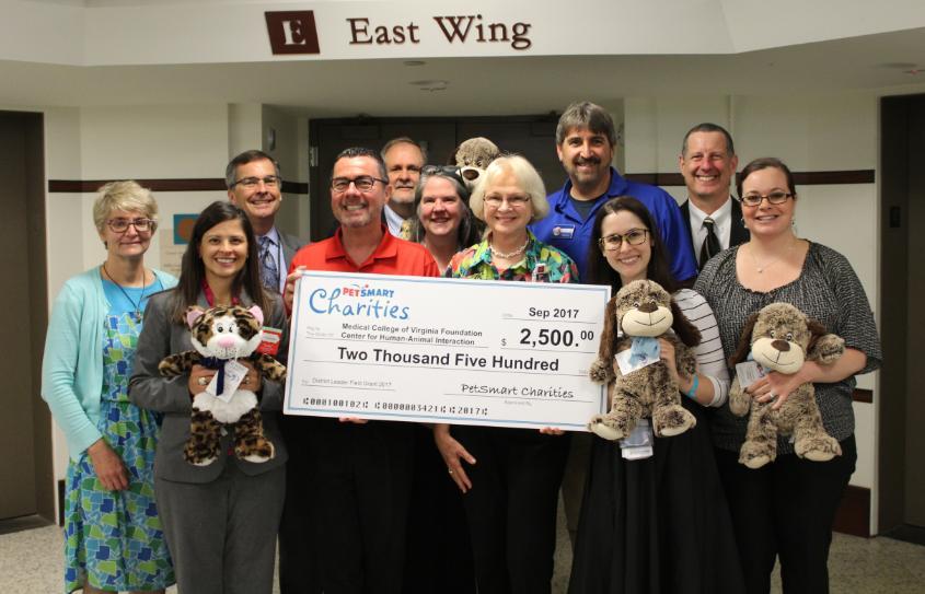 PetSmart managers present The Center for Human-Animal Interaction with an oversized Check for $2,500. PetSmart stuffed animals are also being held.