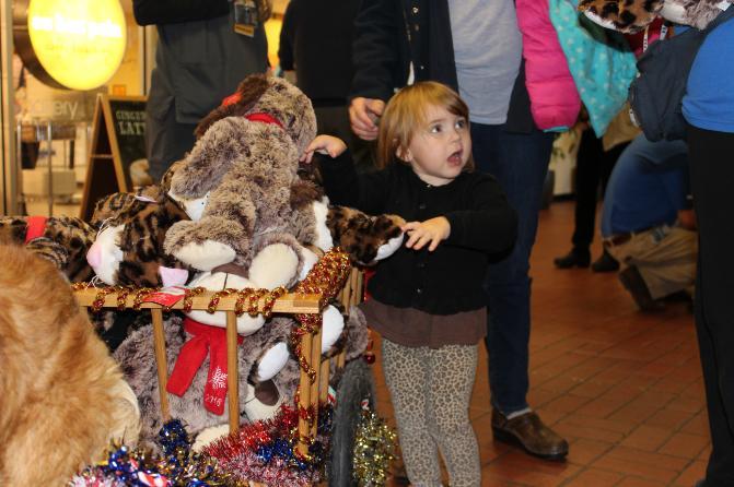 A young child reaches into a cart filled with PetSmart stuffed animals.