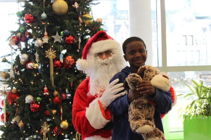 a young child is hugged by Santa Claus as the child holds a PetSmart stuffed dog