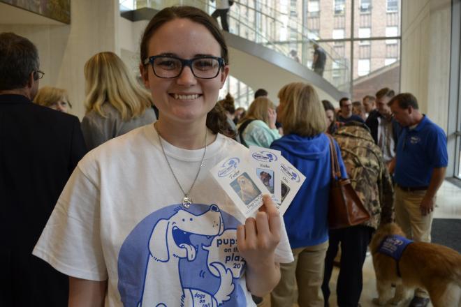 Erin Forgit, the VCU Arts student who designed the 2016 Dogs On Call shirt, holds Dogs on Call trading cards for three therapy dogs