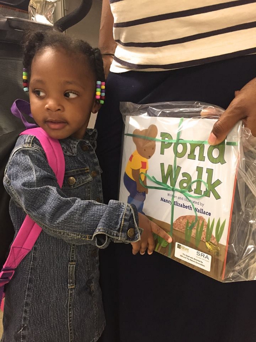 A young child at Childrens Hospital of Richmond points to a book about Earth Day titled 